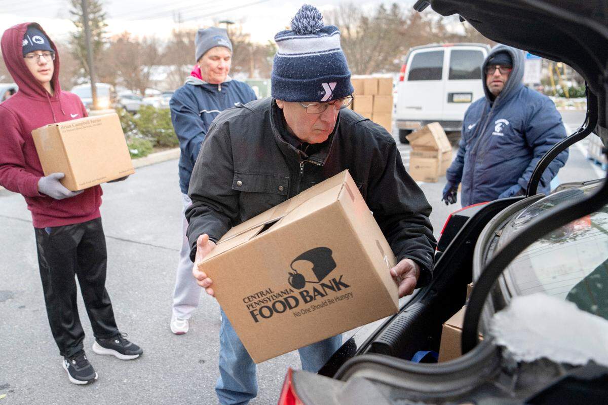 Mel Curtis and fellow volunteers help to load food into a car during the YMCA Anti Hunger Program’s distribution at the Grace Lutheran Church in State College on Thursday, Nov. 17, 2022.