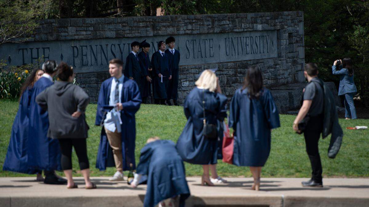 Penn State graduates take photos in front of a university sign on May 6, 2021. The Class of 2022 will receive new diplomas after first receiving diplomas containing the wrong university president’s signature.