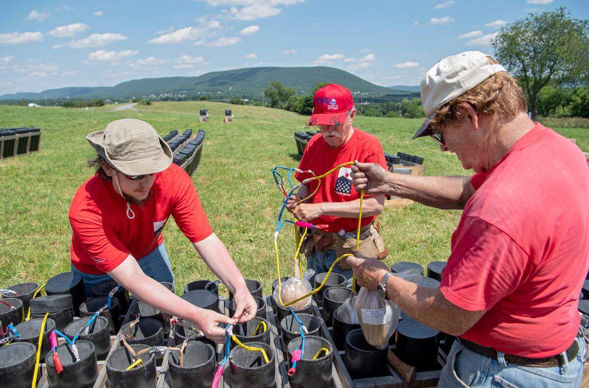 Pyrotechnic volunteers Robert Downey, Bob Mathewson and Rik Harris work together to place firework shells in their respective tubes on June 27 in preparation for the Central PA 4th Fest fireworks show.
