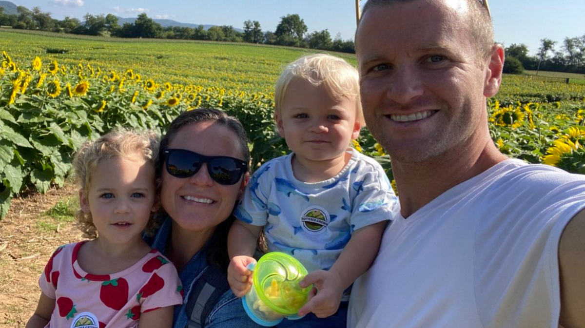 John Valentik, his wife Paige, and their children Charlotte and Parker are pictured exploring a sunflower field.