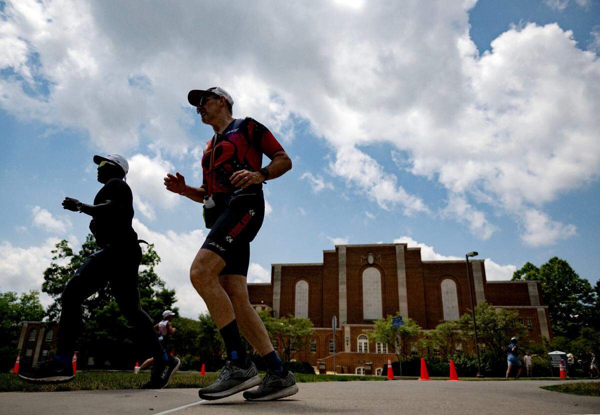 Athletes pass Rec Hall during the 13.1 mile run for the Ironman 70.3 Pennsylvania Happy Valley on Sunday, June 30, 2024.