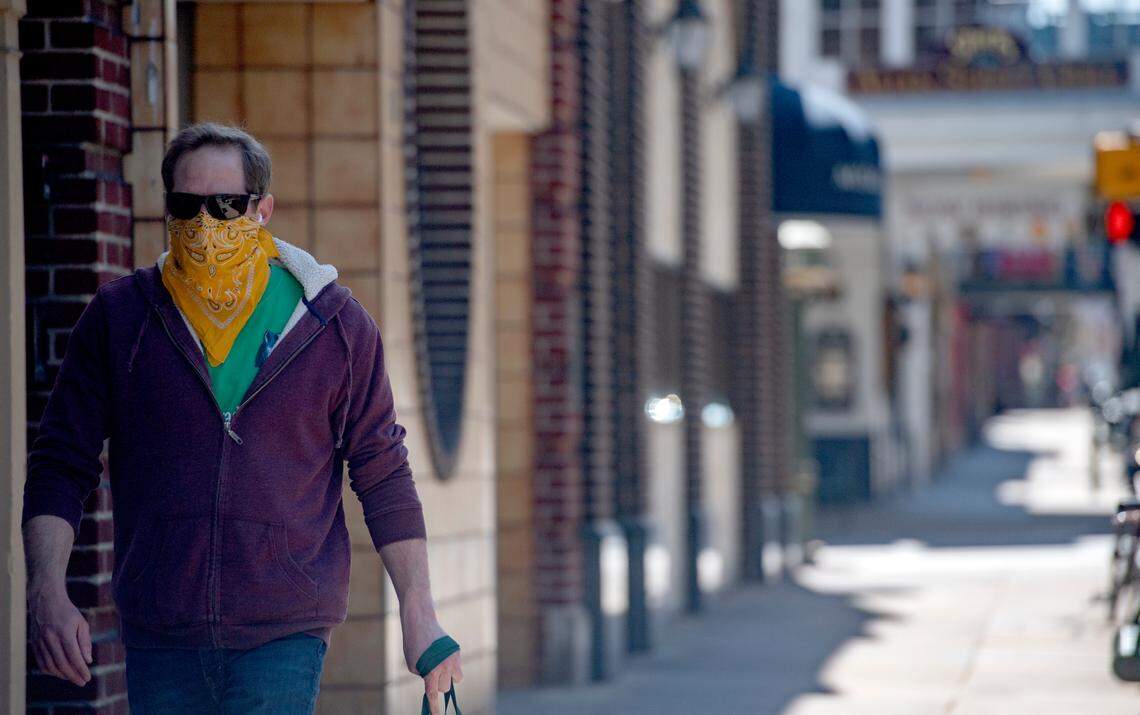 A man walks down College Avenue wearing a bandana for a mask on Monday, April 6, 2020.