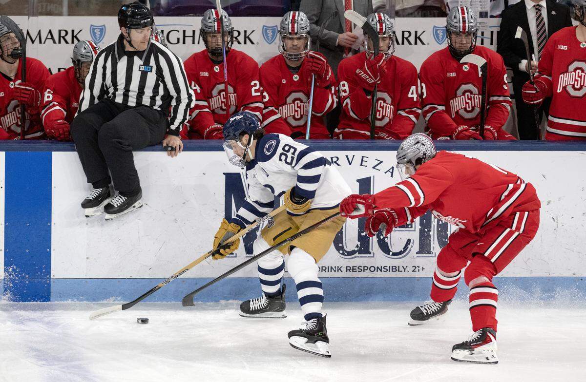 A referee jumps out of the way as Penn State's Reese Laubach skates down the ice with the puck ahead of an Ohio State defender during the game on Friday, Feb. 20, 2026.  