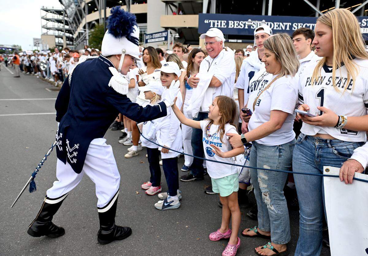Penn State Blue Band drum major Ellie Sheehan high-fives a young fan as they wait for the Penn State football team to arrive at Beaver Stadium for the game against Oregon on Saturday, Sept. 27, 2025.  