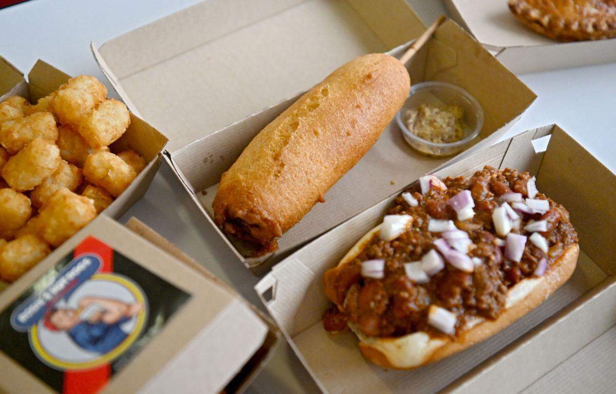 A corn dog with honey mustard and a Rosie’s Big Dog with chili and onions from Rosie’s Hotdogs and Handpies. The corn dog is made with A Rosie’s Big Dog coated in a home made cornmeal batter and flash fried.
