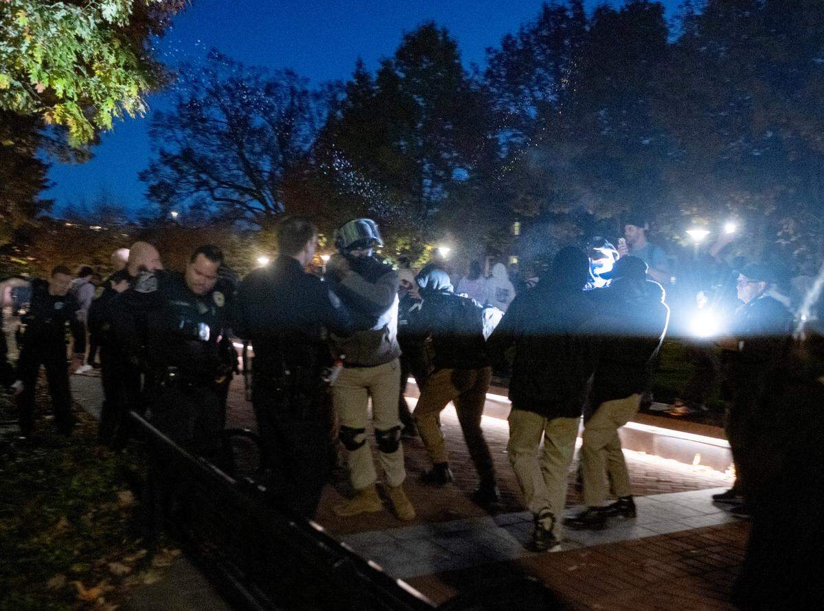 A man sprays bear deterrent at protesters on Monday, Oct. 24, 2022.