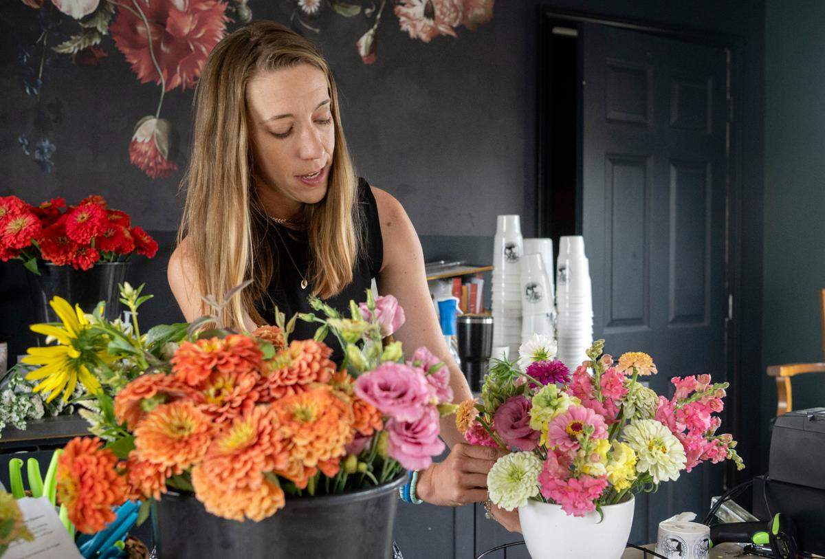 Christie Holloway works on a bouquet in the flower shed at Rooted Farmstead on Friday, Aug. 5, 2022.