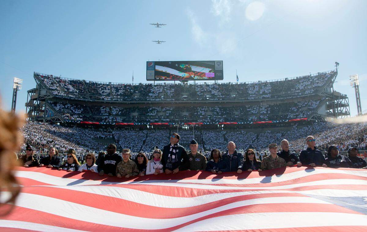 Penn State alumni and members of the ROTC hold a large American flag as two planes flyover before the Penn State football game against Ohio State on Saturday, Oct. 29, 2022.