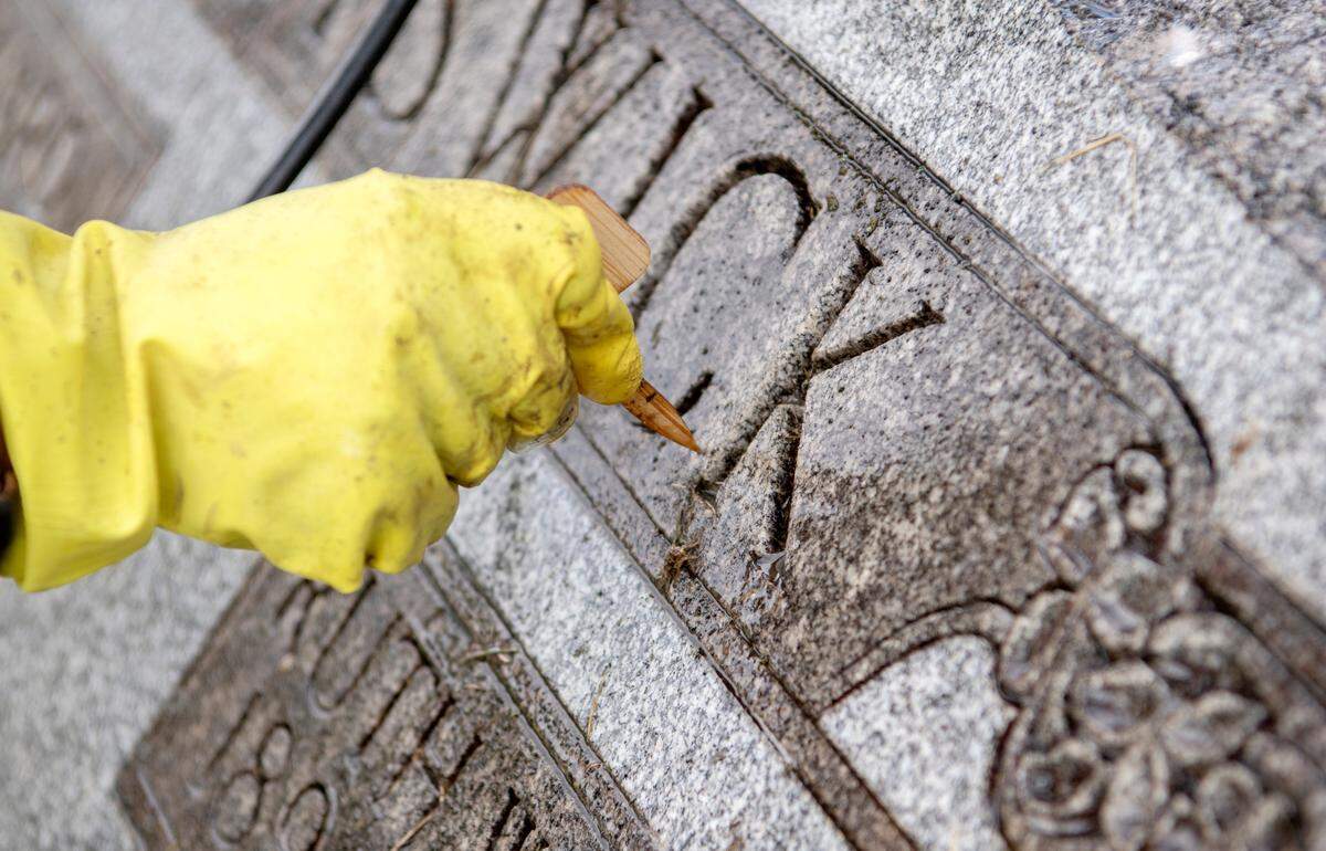 Renea Nichols uses a tool to clean the debris out of the engravings on a tombstone at the Union Cemetery on Thursday.