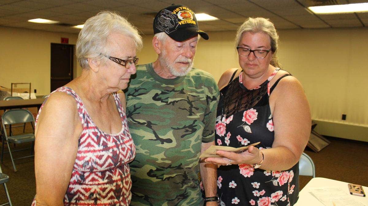 From left, Shirley Schweitzer, her husband and Vietnam veteran Jesse Schweitzer and his daughter Jamey Baker look at a photograph from his time in the service that was recently found at a Watsontown home after it was lost three years earlier.