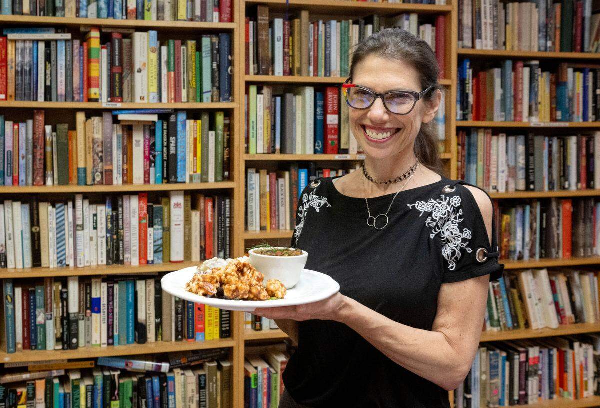 Elaine Meder-Wilgus holds vegetarian meal of BBQ cauliflower and mushroom gumbo at Websters Bookstore Cafe on Wednesday, July 17, 2024.