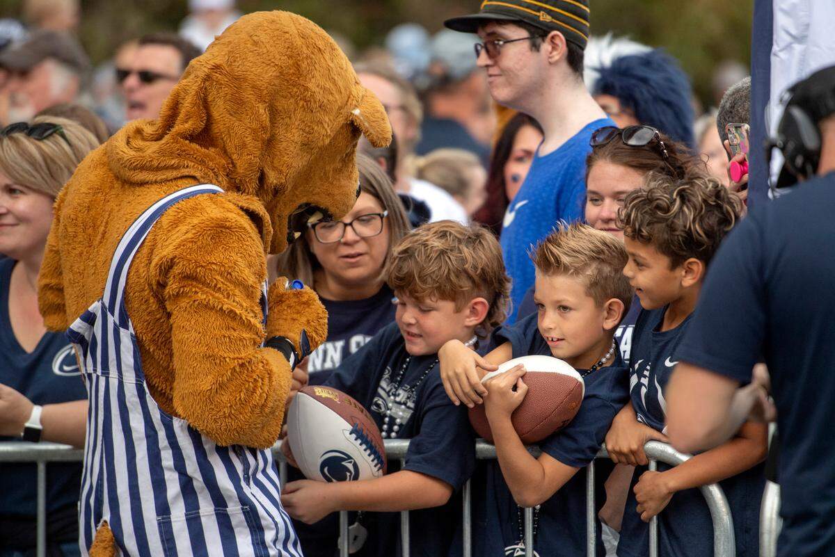The Nittany Lion autographs a football for young fans before the Penn State football team arrives at Beaver Stadium.