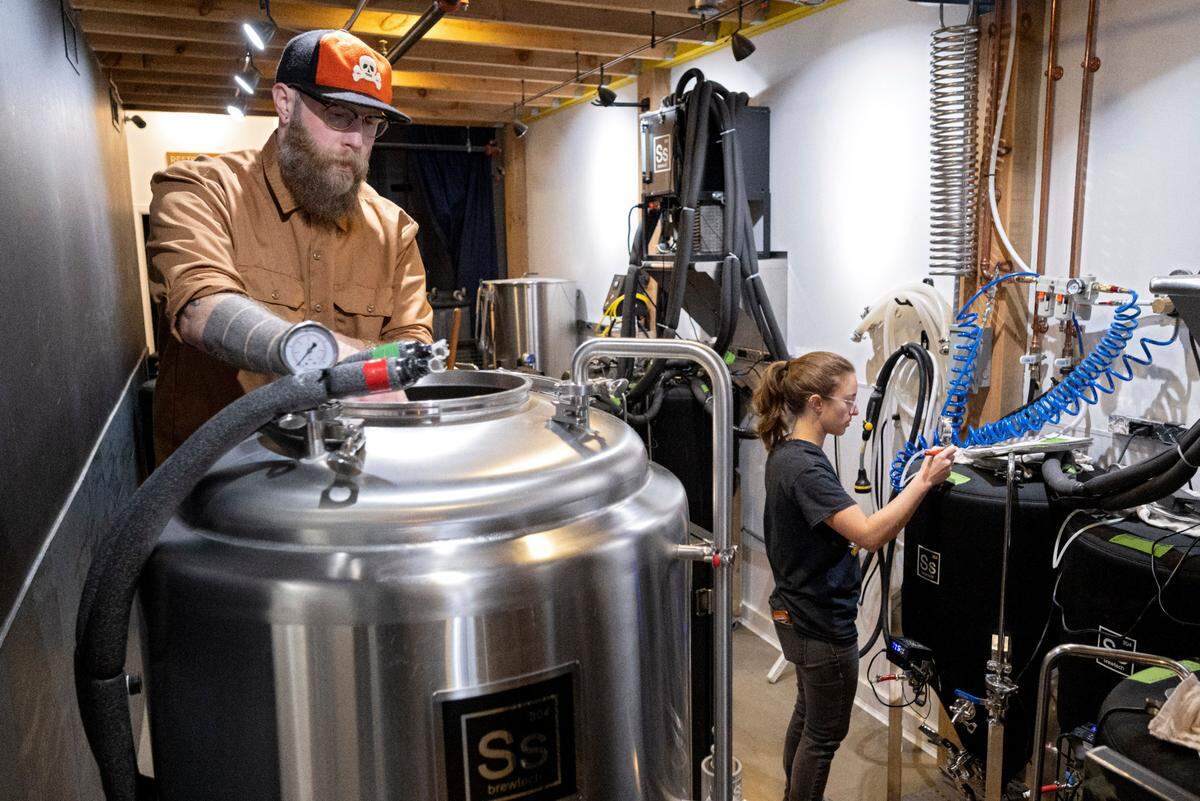 Matt Simon cleans out a beer tank as Katie Legenski tests a batch of kombucha at Antifragile Brewing Company on Tuesday, Nov. 28, 2023.