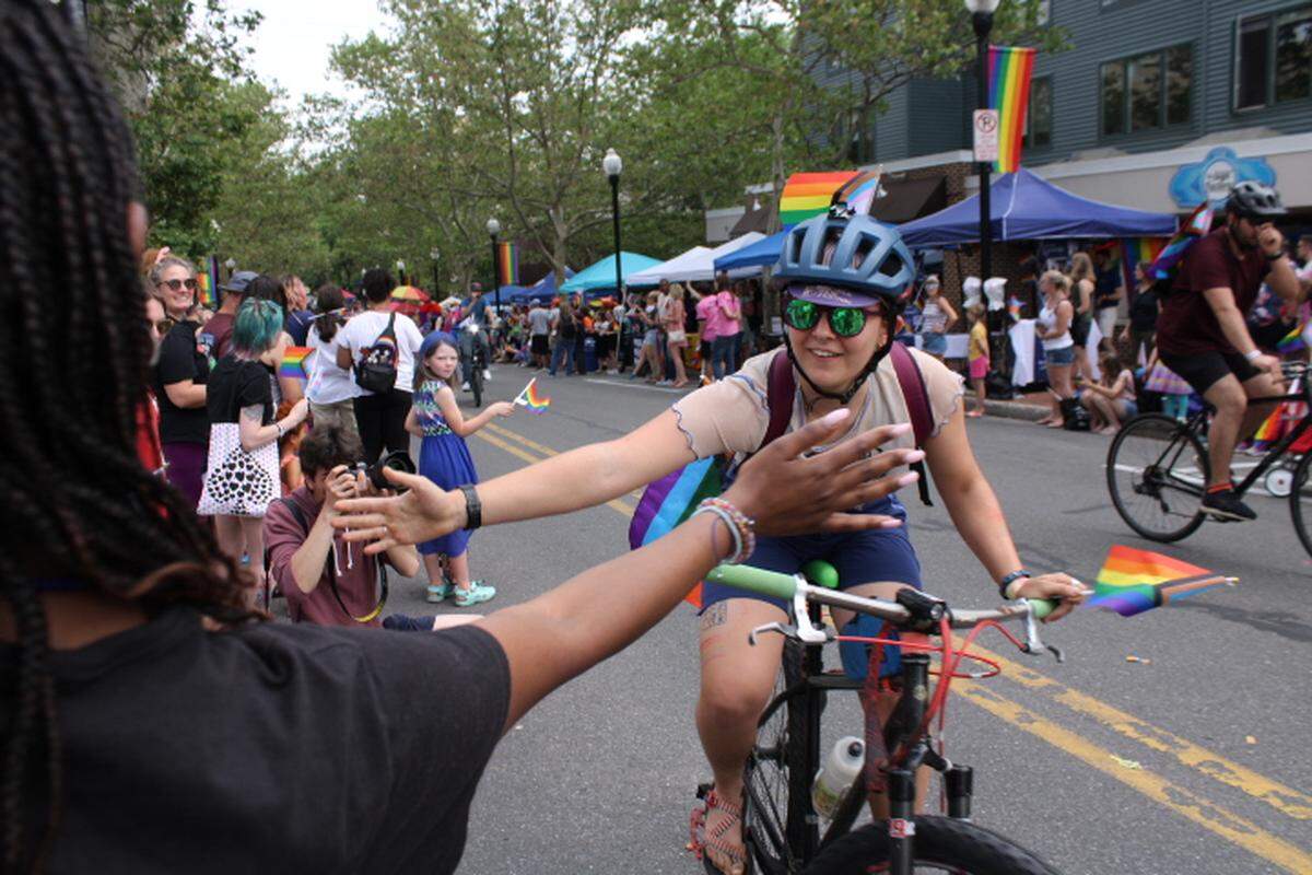 A bicyclist in the State College Pride Parade stops to give onlookers high-fives on Saturday, June 10, 2023.