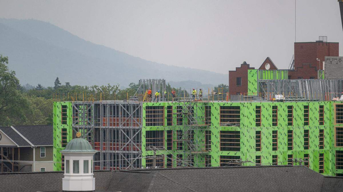 Mount Nittany is seen through the haze past construction crews working on the new building on Pugh Street on Monday, July 17, 2023.