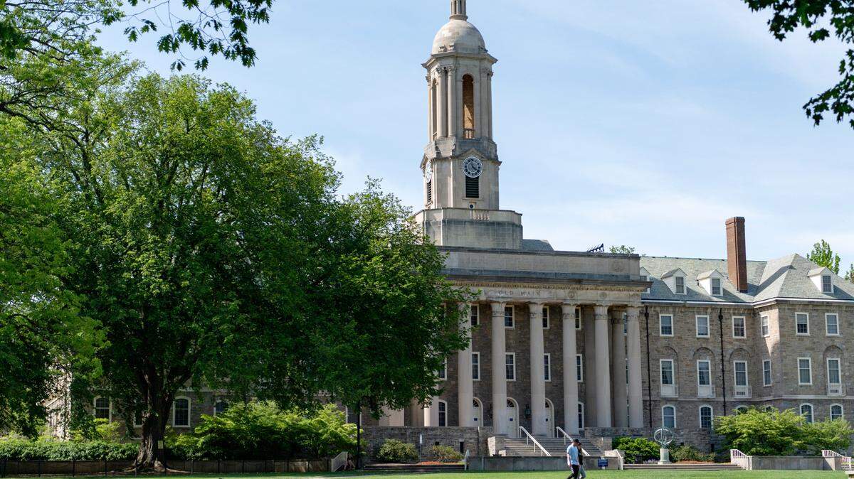 People walk across Old Main lawn on the Penn State campus on Wednesday, May 19, 2021.