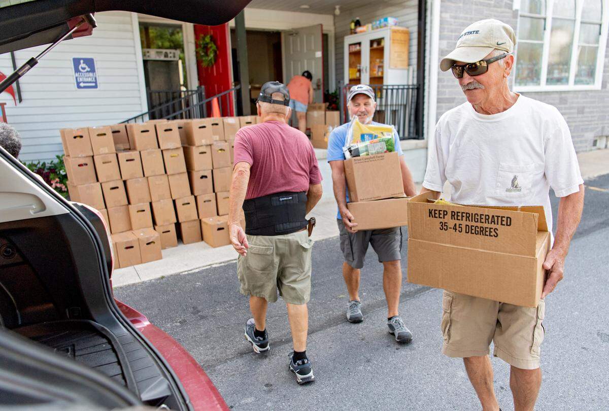 Craig Alter and fellow volunteers help to load food into cars as part of the YMCA food distribution at the Howard United Methodist Church on Thursday, July 7, 2022.