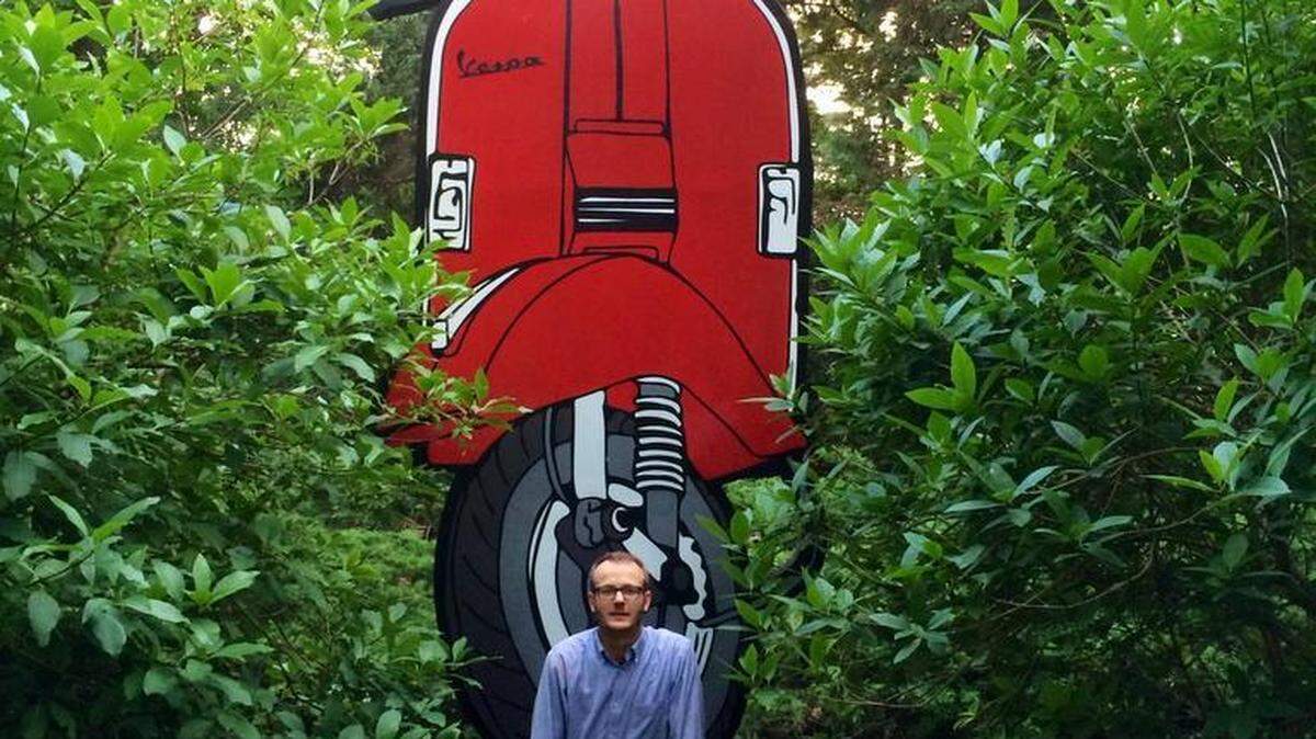 Local artist William Snyder sits in front of his 2-D sculpture #BigVespa, an homage to the iconic scooter, at the Rhoneymeade Sculpture Garden. 

