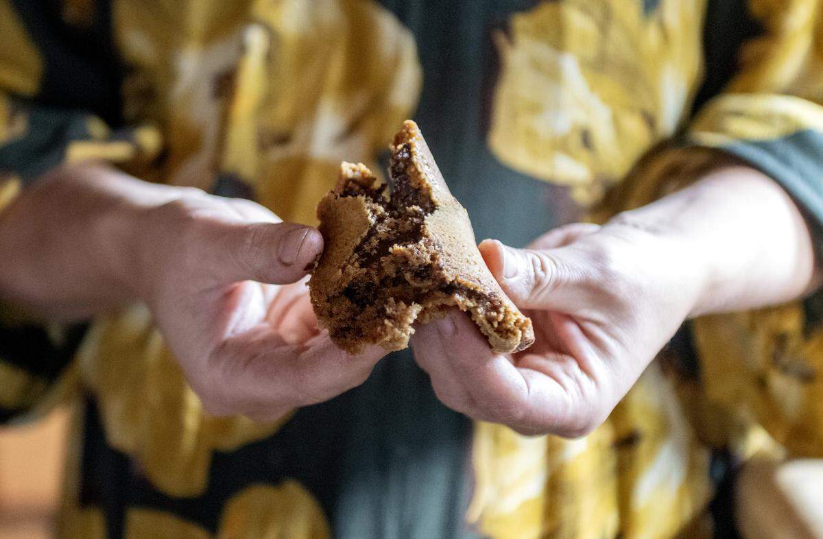Alyssa Burns of Blackberry Cottage Bake Shoppe breaks a chocolate chip cookie on Friday, Nov. 14, 2025. The cookies are made with organic einkorn flour and no refined sugars.  
