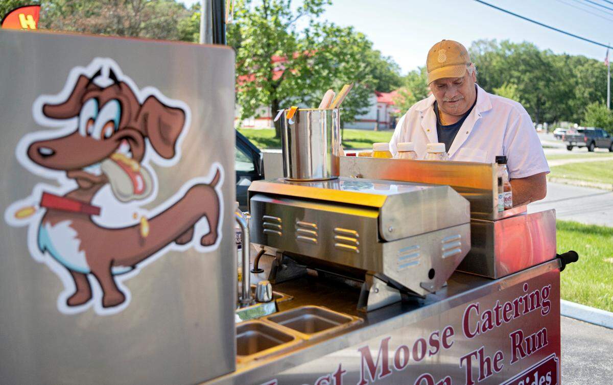 Bob Vogely makes an order for a customer at his Dog’s on the Run hot dog cart outside of Tire Town on Thursday, Aug. 31, 2023.