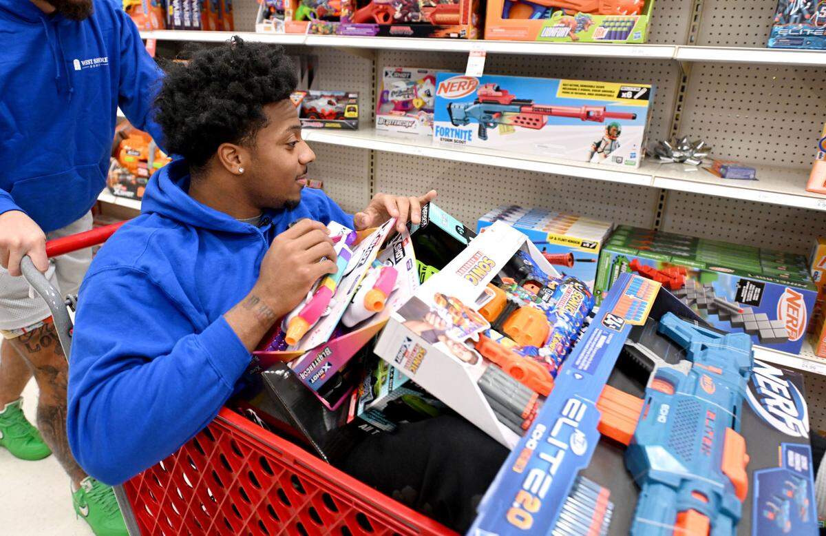 Penn State linebacker DaKarri Nelson sits in a shopping cart covered in toys as he and teammate Julian Fleming make their way through the aisles at Target in State College on Monday, Dec. 2, 2024.