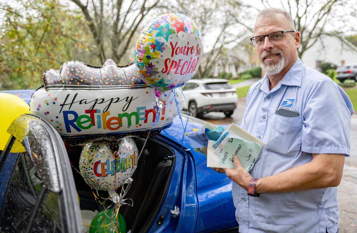 Balloons fill Jon Kolesar’s car Monday as he holds a stack of cards from his last day as a mail carrier. Some neighborhoods he delivered to included the Clover Highlands neighborhood, which decorated their mailboxes to honor his retirement.