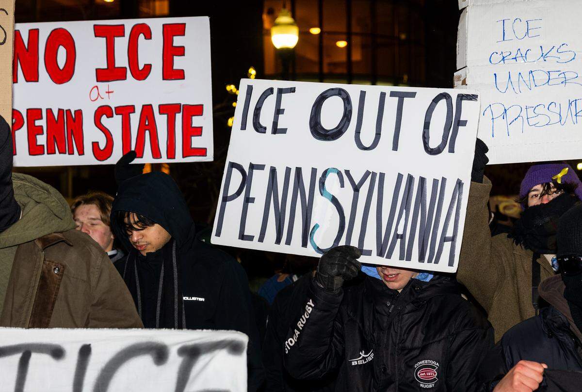 Protesters hold up anti-ICE signs during a march through downtown State College on Monday. The protest was organized after the fatal shooting of Alex Pretti in Minneapolis.