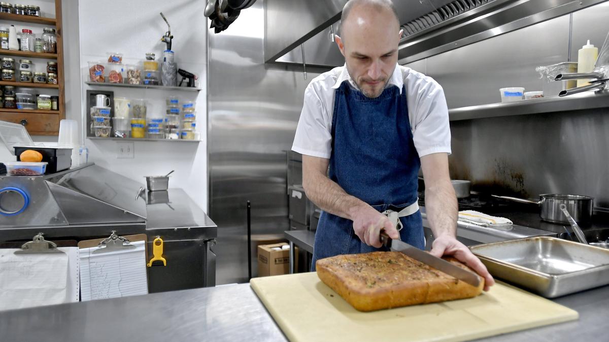 Quintin Wicks of Revival Kitchen cuts a loaf of fresh focaccia bread on Wednesday as he prepares for a dinner.