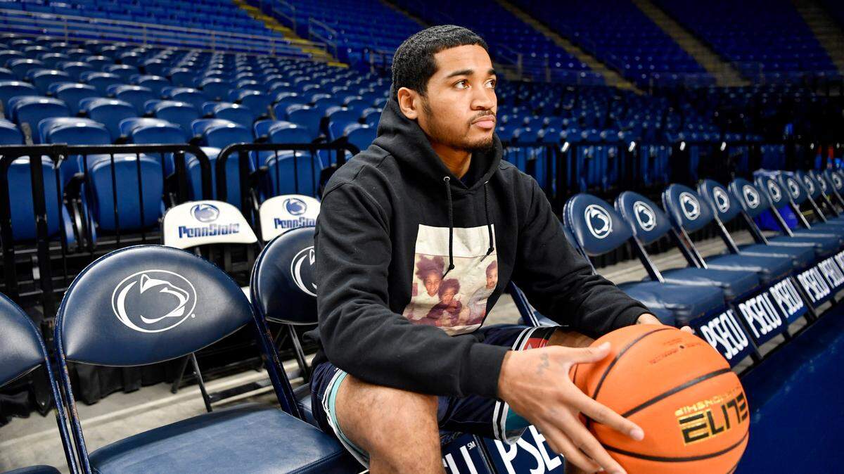 Penn State men’s basketball player Sam Sessoms wears a sweatshirt with photos of his family on it as he looks over the court at the Bryce Jordan Center.