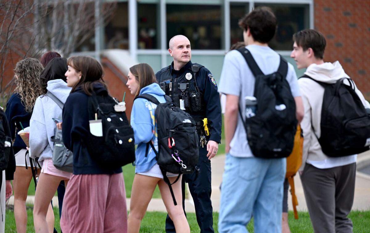 A police officer wathces as students line up to enter State College Area High School with extra safety measures on Monday, April 14, 2025. Students had to enter through a metal detector and have their bags checked.