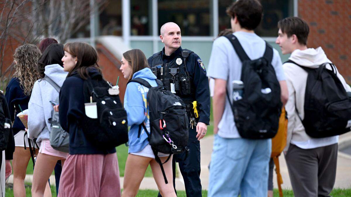 A police officer watches as students line up to enter State College Area High School with extra safety measures on Monday, April 14, 2025. Students had to enter through a metal detector and have their bags checked.  