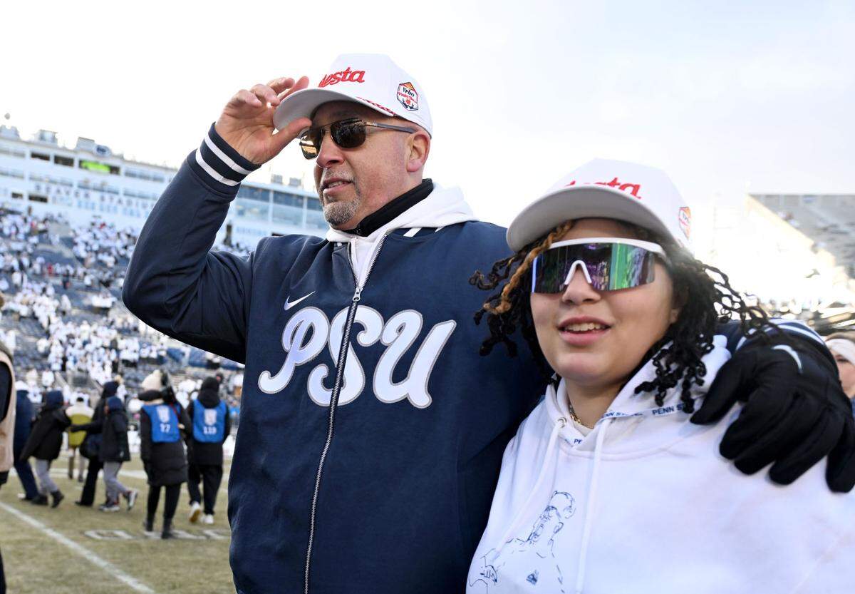 Penn State football coach James Franklin puts on a Fiesta Bowl hat as he walks with his daughter after the win over SMU in the first round of the College Football Playoff on Saturday, Dec. 21, 2024 at Beaver Stadium.