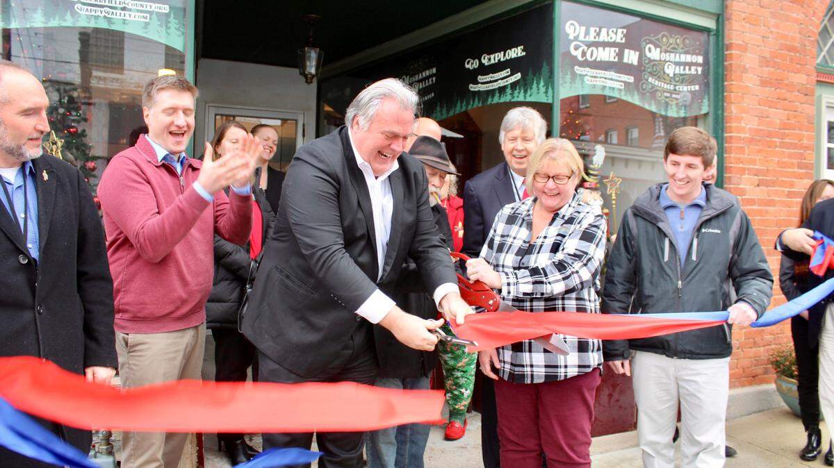 Fritz Smith, CEO of Happy Valley Adventure Bureau, and Sue Swales-Vitullo, executive director of Visit Clearfield County, help cut the ribbon for the new Moshannon Valley Heritage Center in Philipsburg on Friday.