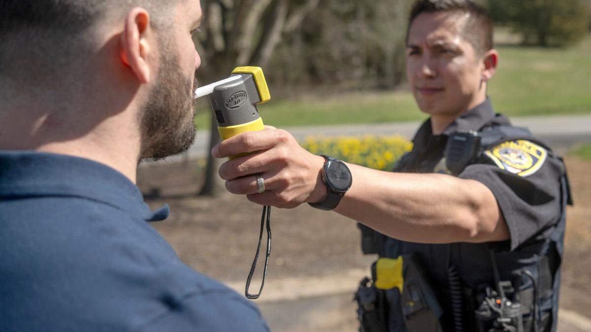 A police officer and intern demonstrate a breathalyzer test.
