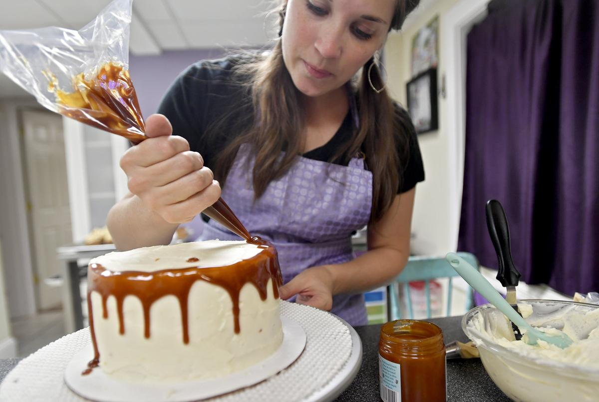 Melissa Stitzer of The Cakery, which is coming to a storefront in Bellefonte this spring, does a caramel drip on a carrot cake with cream cheese icing on Wednesday, Sept. 26, 2018.