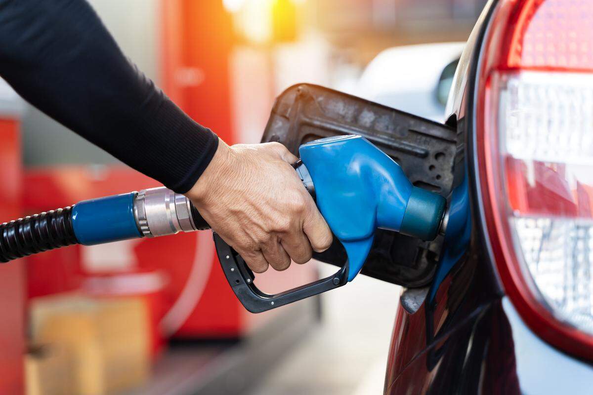 A man refueling the car at a gas station fuel pump.