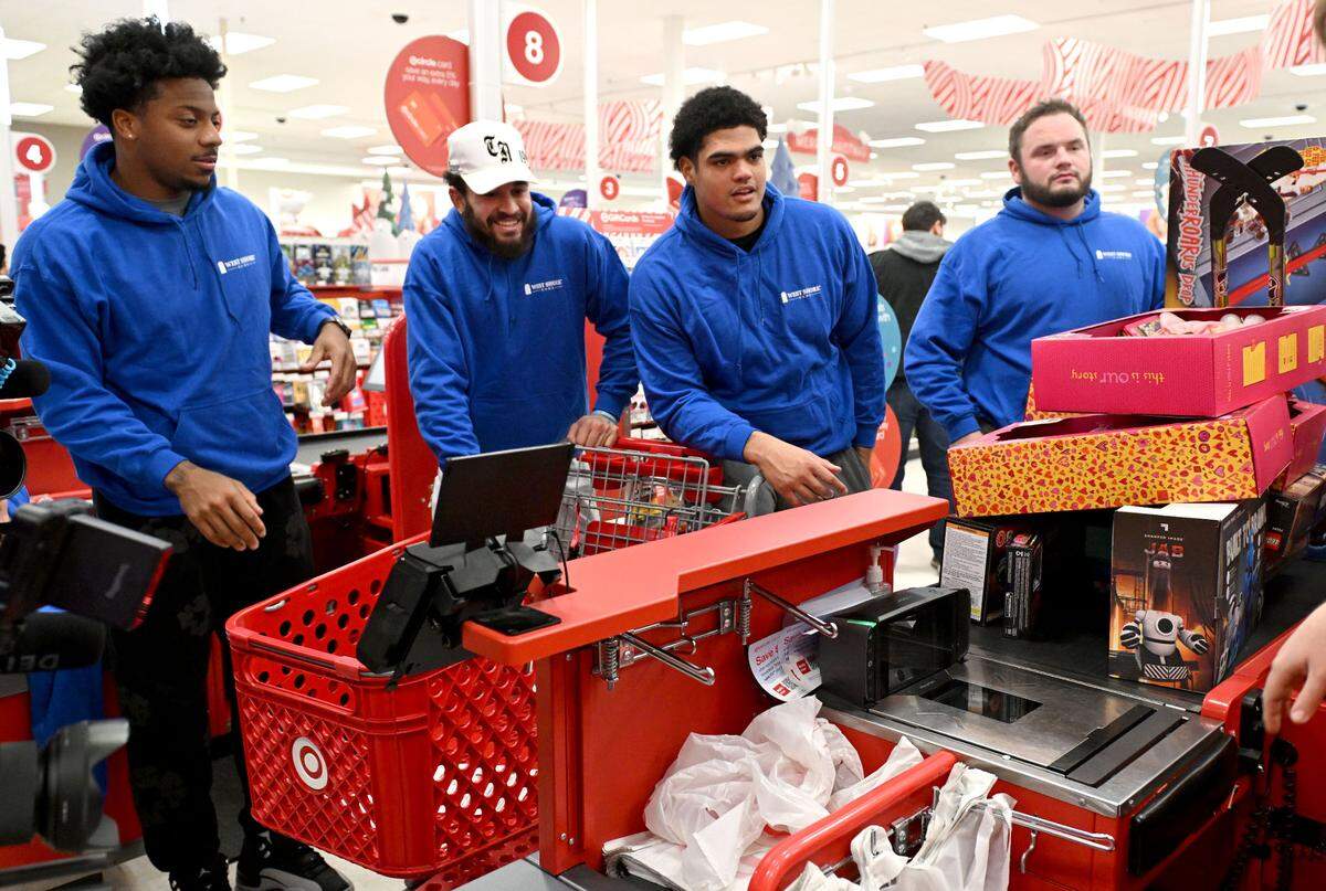 Penn State football players DaKarri Nelson, Julian Fleming, Drew Shelton and Dominic Rulli watch in anticipation as they toys they picked out for Toys for Tots are scanned at the checkout at Target on Monday, Dec. 2, 2024.