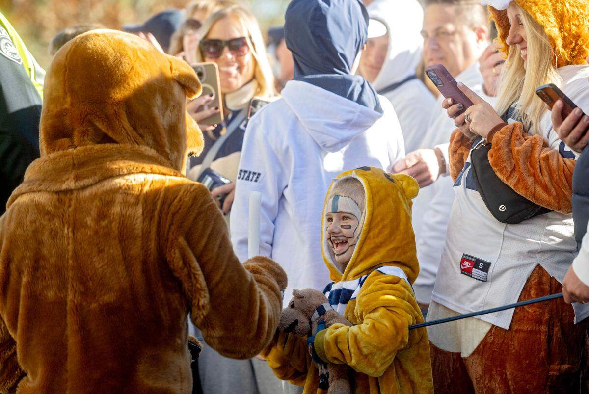 A young fan interacts with the Penn State Nittany Lion as the football team arrives at Beaver Stadium for the game against Ohio State on Saturday, Nov. 2, 2024.
