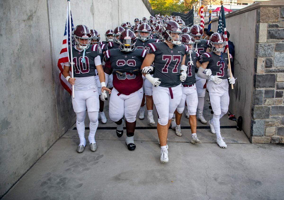 The State College football links arms as they walk down the ramp to Memorial Field for the game against Downingtown East on Friday, Sept. 1, 2023.