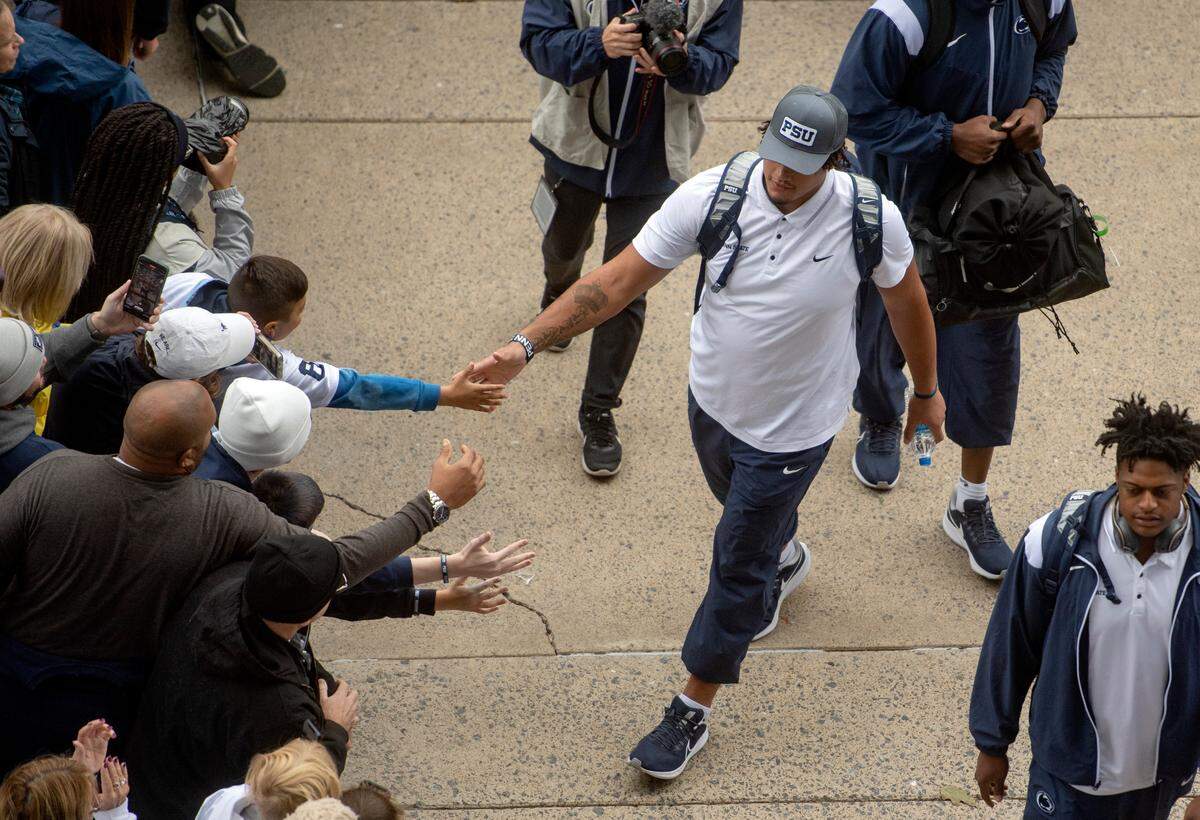 Penn State football players wave and high five fans as they arrive at Beaver Stadium for the game on Saturday, Oct. 1, 2022.