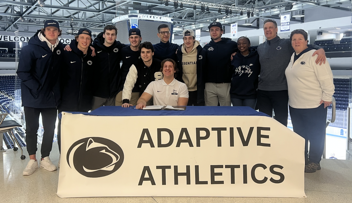 Penn State men’s hockey team, Brandi Stuart, Guy Gadowsky and Brenna O’Connor take a picture with Max Malec after his signing ceremony in Pegula Ice Arena.