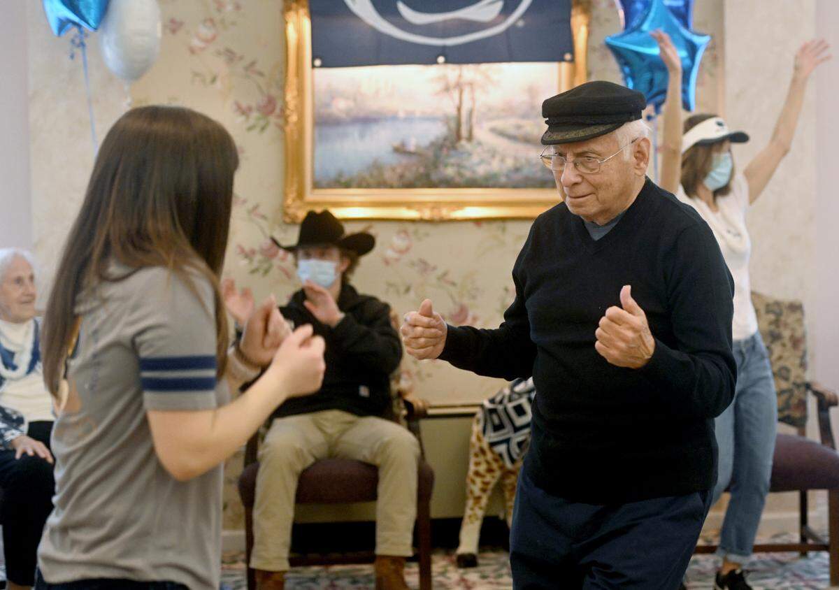 Cat Rokavec-Hirsh dances with Bob Rodino during the 46-minute mini-Thon celebration at Juniper Village at Brookline senior living on Monday.