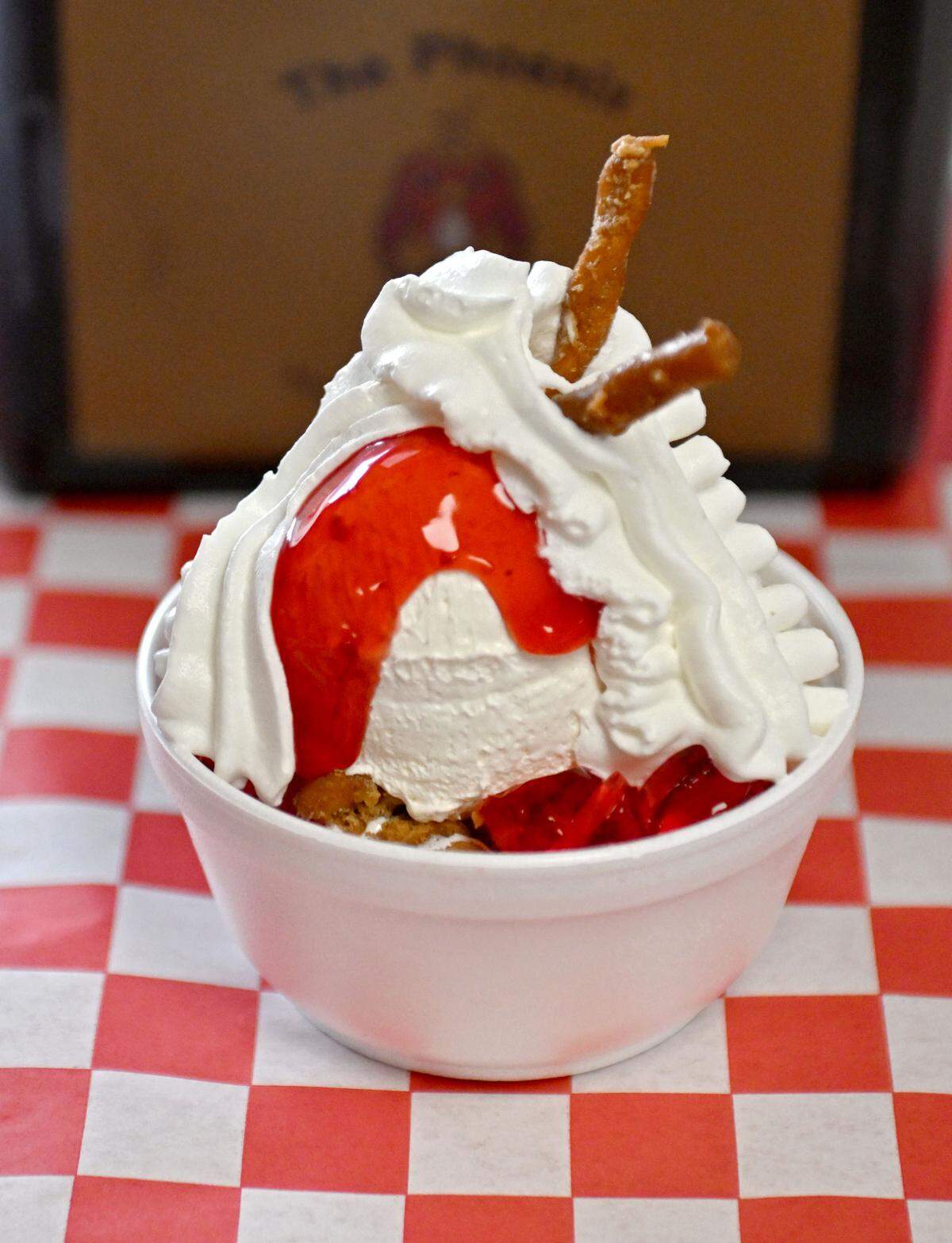 A strawberry pretzel sundae at The Phoenix features cheesecake filling over soft serve and candied pretzels, along with strawberry jello and strawberry topping. 
