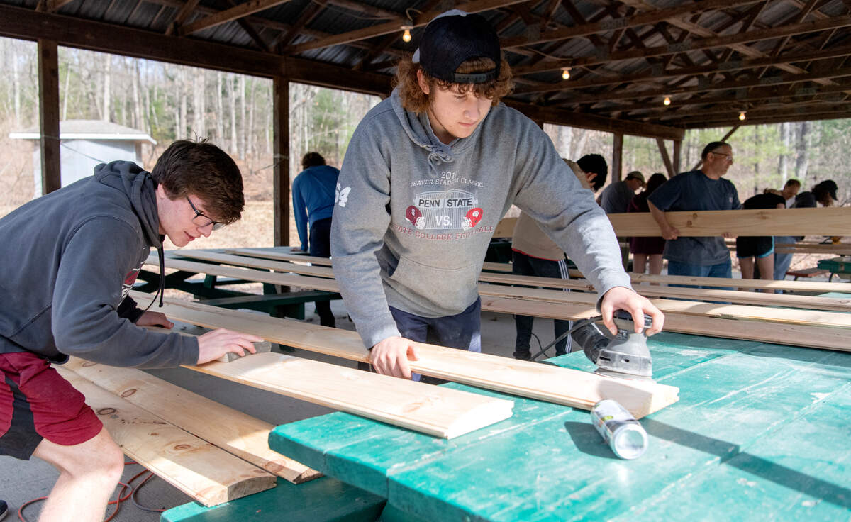Andrew McChesney, Michael Inham and fellow scouts from Troop 32 work together on March 19 to sand wood for the siding of the new David O’Connell Health Education Building at Seven Mountain Scout Camp.