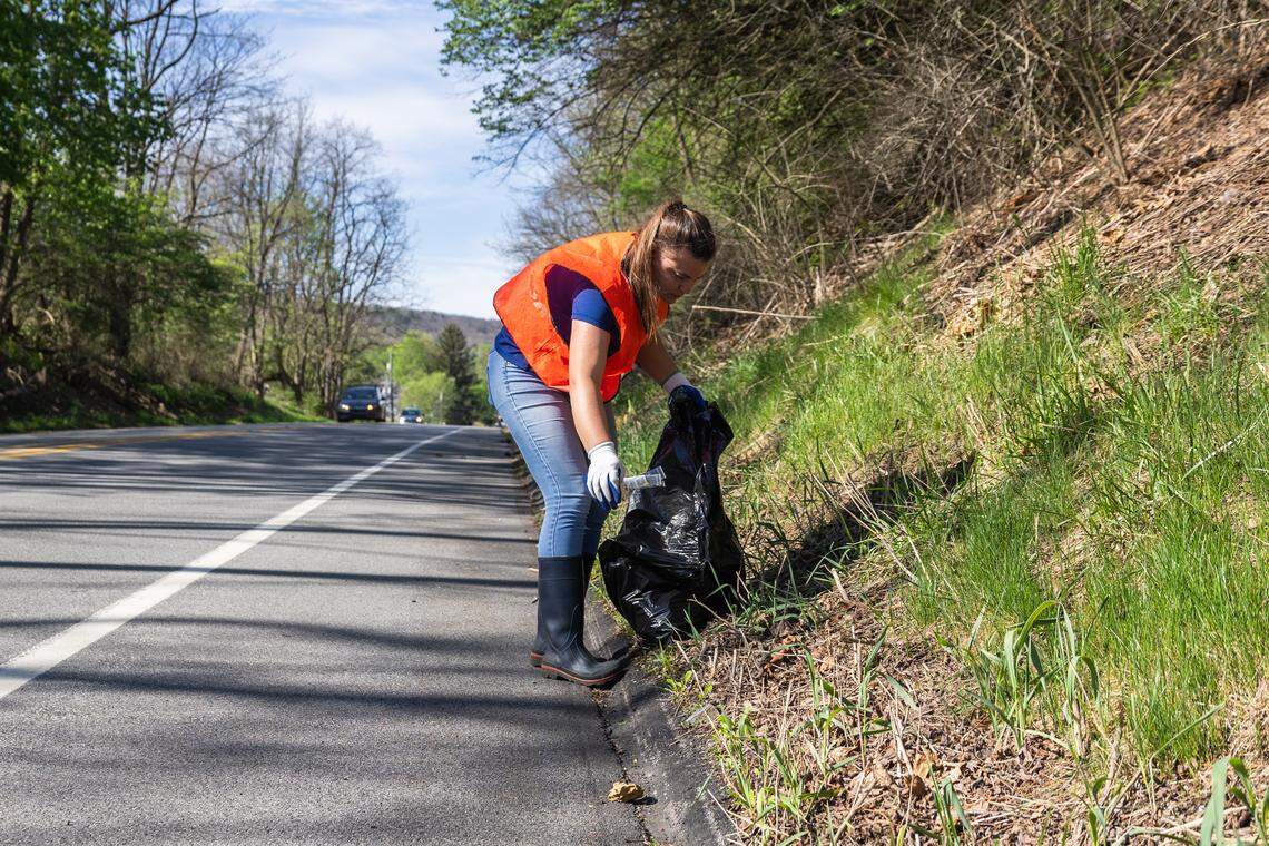 Volunteer Emily Rojik picks up trash in Pine Grove Mills, Pa., on Saturday, April 18, 2026. The ClearWater Conservancy organized volunteers across Centre County to clean up public green spaces.