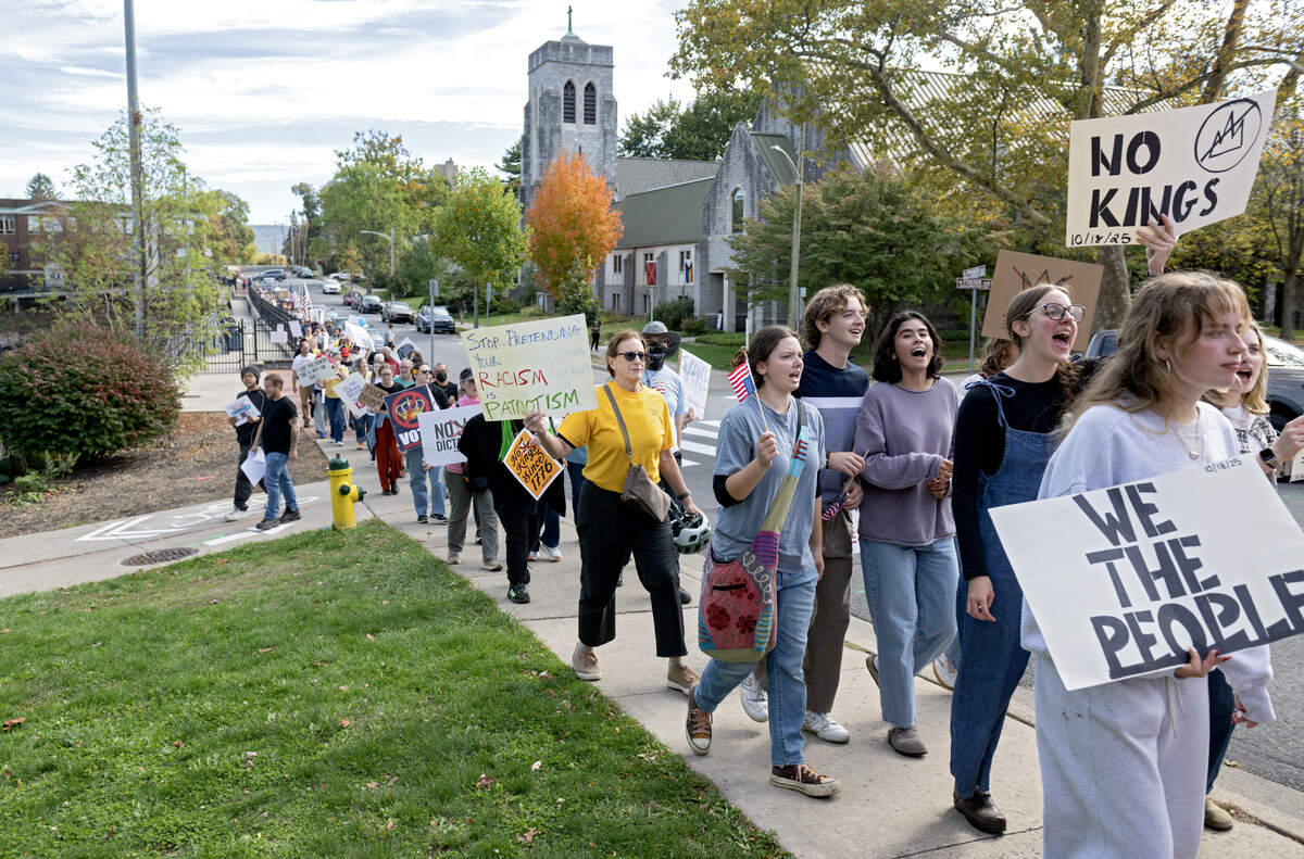 Protesters marched on the sidewalks along Fraser Street as part of the No Kings anti-Trump rally on Saturday, Oct. 18, 2025.