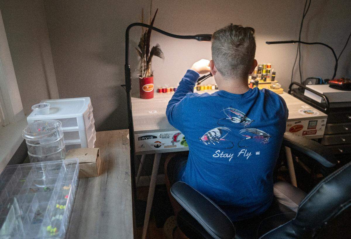 Landis Sampsel, 12, makes makes a collection of fly fishing flies at his desk on Thursday, July 13, 2023.