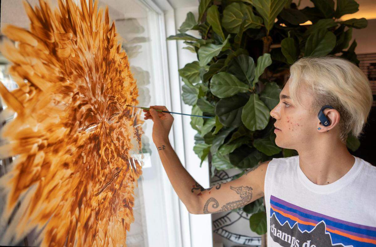 Derek Ulrich works on his sunflower painting in the window of 3 Dots on Thursday, July 28, 2022. Artists have painted windows in State College business for the Downtown Improvement District’s Sunflower Solidarity with Ukraine initiative.