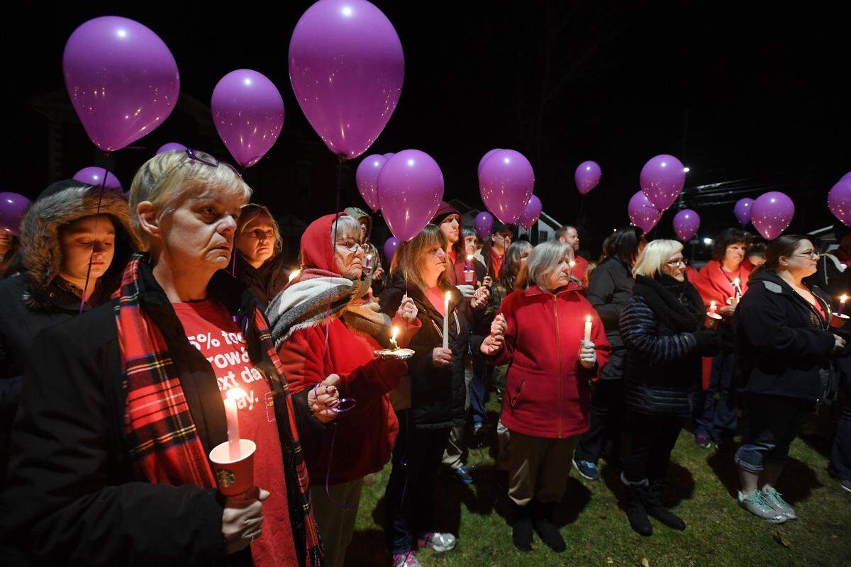 People hold candles and purple balloons before the balloon release during a candlelight vigil for the Schultz family in November 2017 at Osceola Mills Community Park.