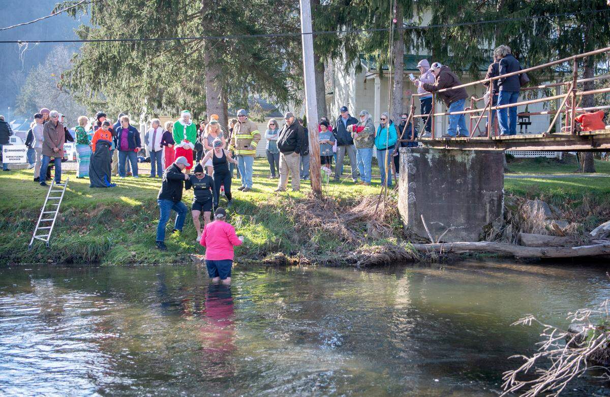 “Super plungers,” who went underwater three times, wade into Penns Creek on Saturday with cheers from the crowd during the YMCA of Centre County Polar Bear Plunge.